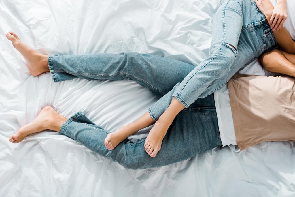 обрезанное изображение молодой пары лежащей на кровати в спальне
 - Фото, изображение
