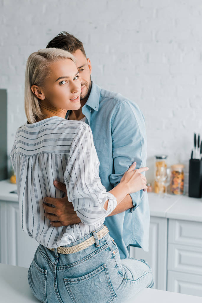 sensual young couple hugging in kitchen, girlfriend looking at camera - Photo, Image