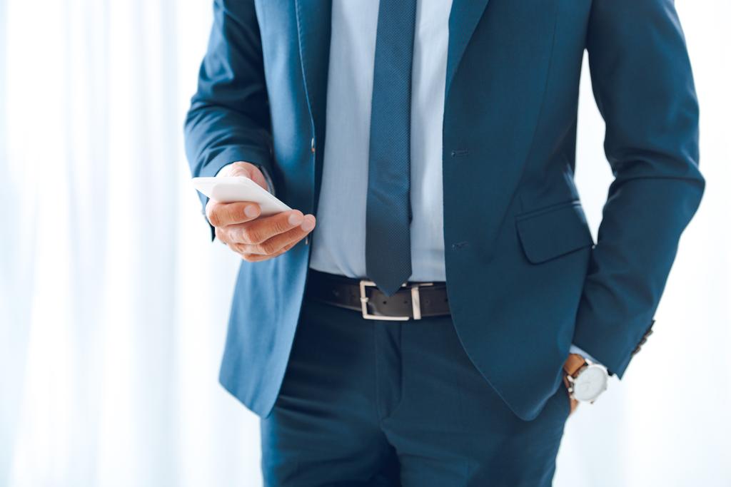 обрізаний знімок бізнесмена у формальному носінні за допомогою смартфона
 - Фото, зображення