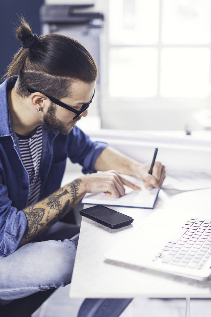 Jeune homme élégant caucasien designer écriture à son bureau
. - Photo, image