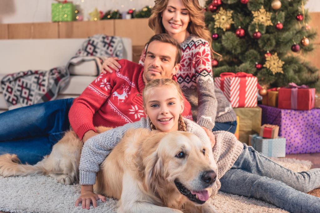famiglia felice con cane golden retriever sdraiato vicino all'albero di Natale a casa
 - Foto, immagini