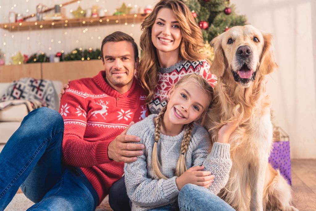família sorridente com cão retriever dourado sentado perto da árvore de natal com presentes
 - Foto, Imagem
