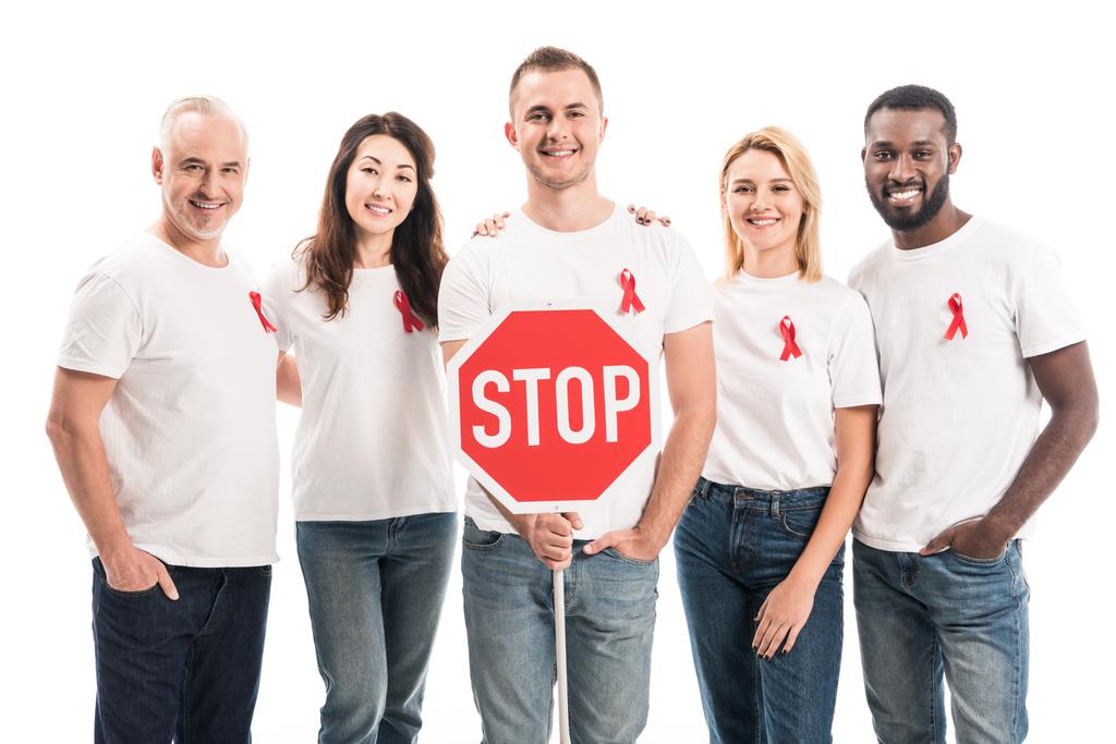 group of people in blank white t-shirts with aids awareness red ribbons and stop road sign looking at camera isolated on white - Photo, Image