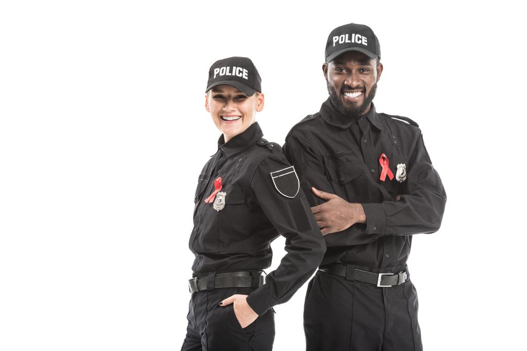 jistý policistů s aids povědomí červené pásky při pohledu na fotoaparát izolované na bílém - Fotografie, Obrázek