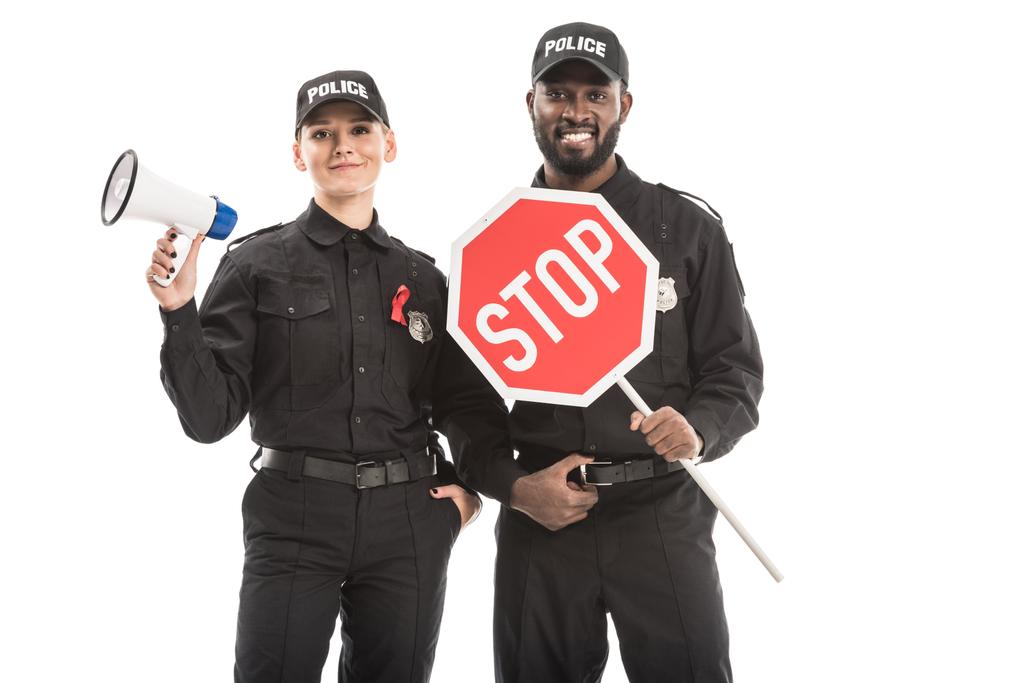 agentes de policía sonrientes con señal de stop road y megáfono mirando a la cámara aislada en blanco, SIDA concepto de conciencia
 - Foto, Imagen