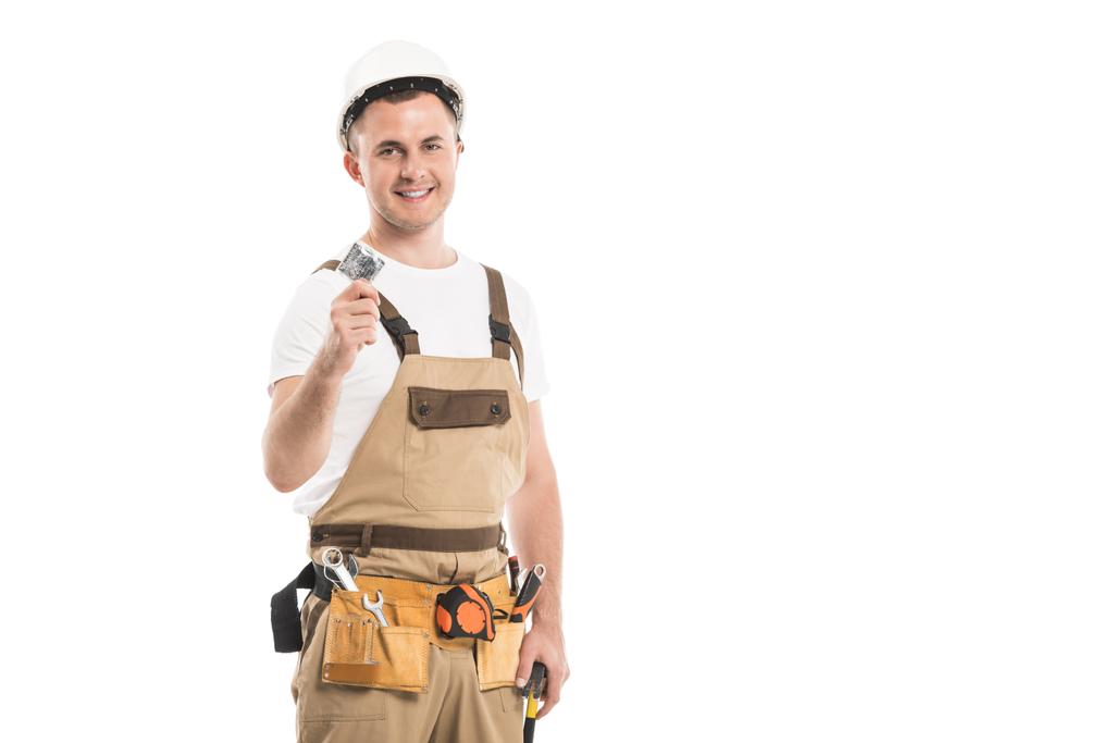 красивый взрослый строитель, держащий презерватив и смотрящий на камеру, изолированную на белом
 - Фото, изображение
