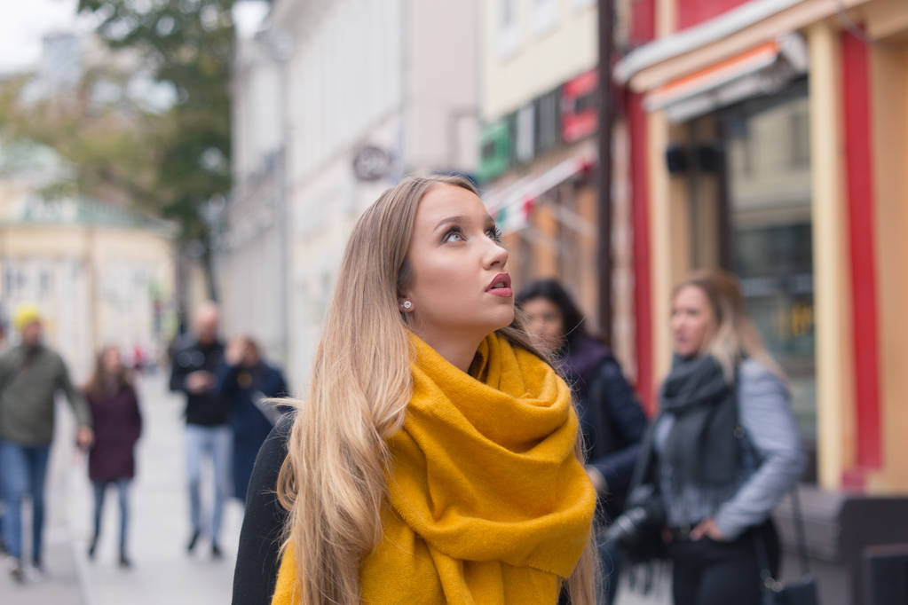 古いモスクワの歴史的な中心部にドイツ観光の女の子。コートと黄色のスカーフで長髪の金髪の女性. - 写真・画像