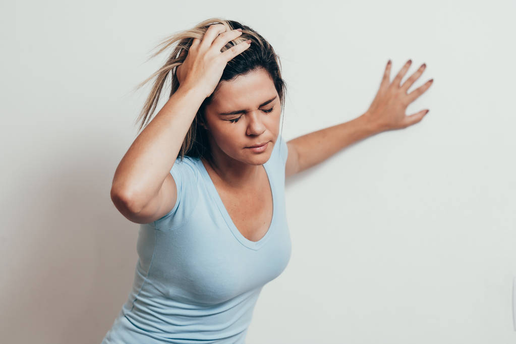 Vrouw lijden van duizeligheid moeilijk opstaan terwijl leunend op muur - Foto, afbeelding