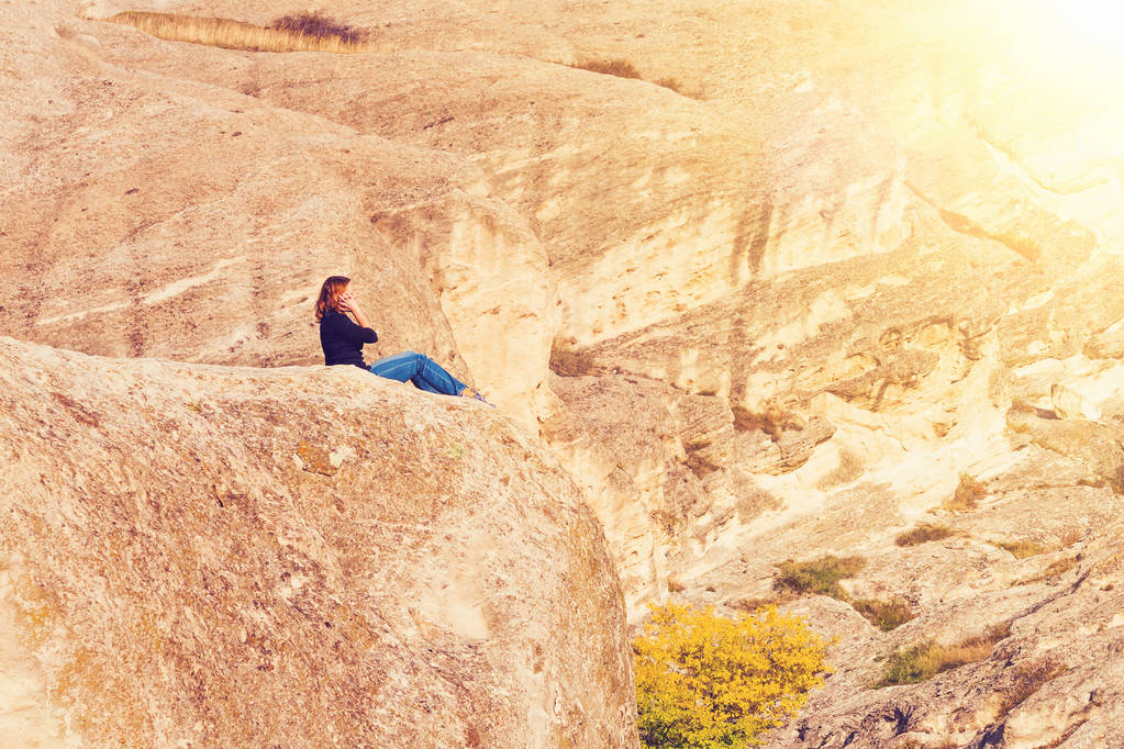 Frau sitzt auf dem Gipfel eines Berges im Sonnenlicht - Foto, Bild