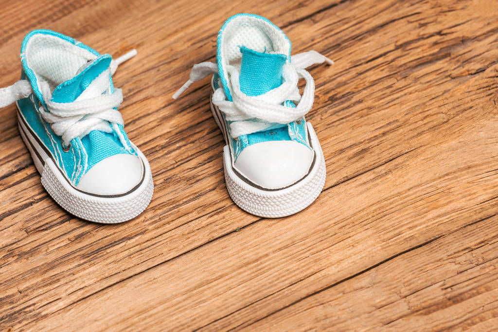 Toy blue sneakers on old wooden surface - Photo, Image