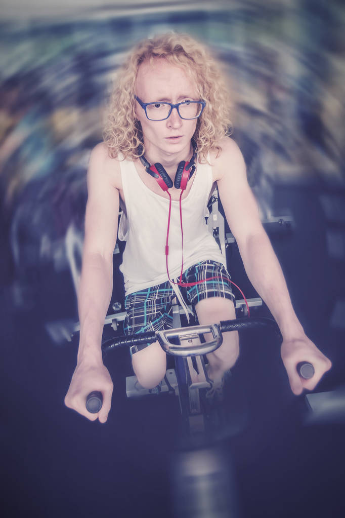 Hombre rubio con gafas en una bicicleta estacionaria
 - Foto, Imagen