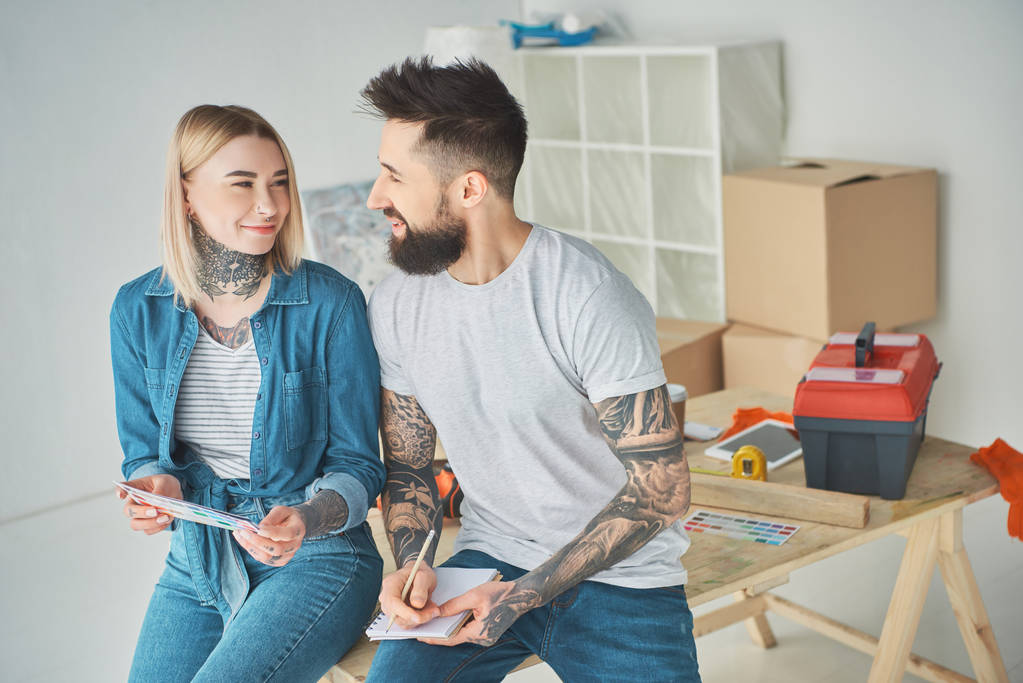 šťastný mladý pár se drží barevnou paletu a notebook v novém domě - Fotografie, Obrázek