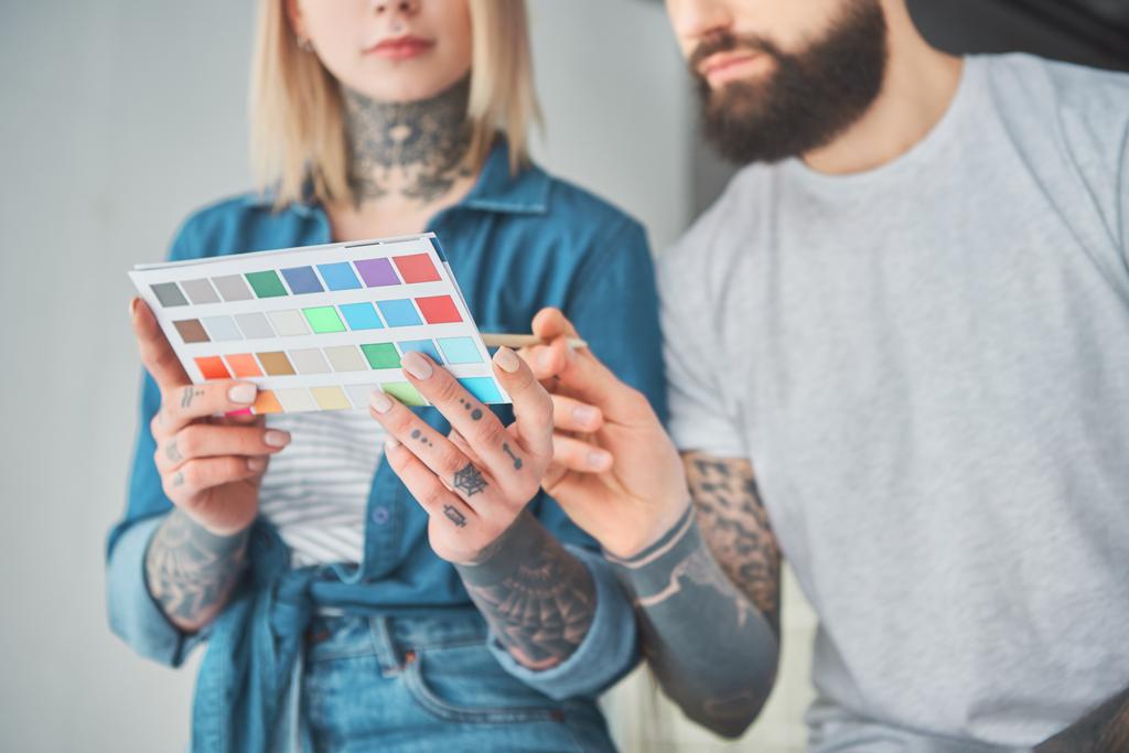 ritagliato colpo di giovane coppia tatuata in possesso di tavolozza di colori e la scelta del colore per il miglioramento della casa
 - Foto, immagini