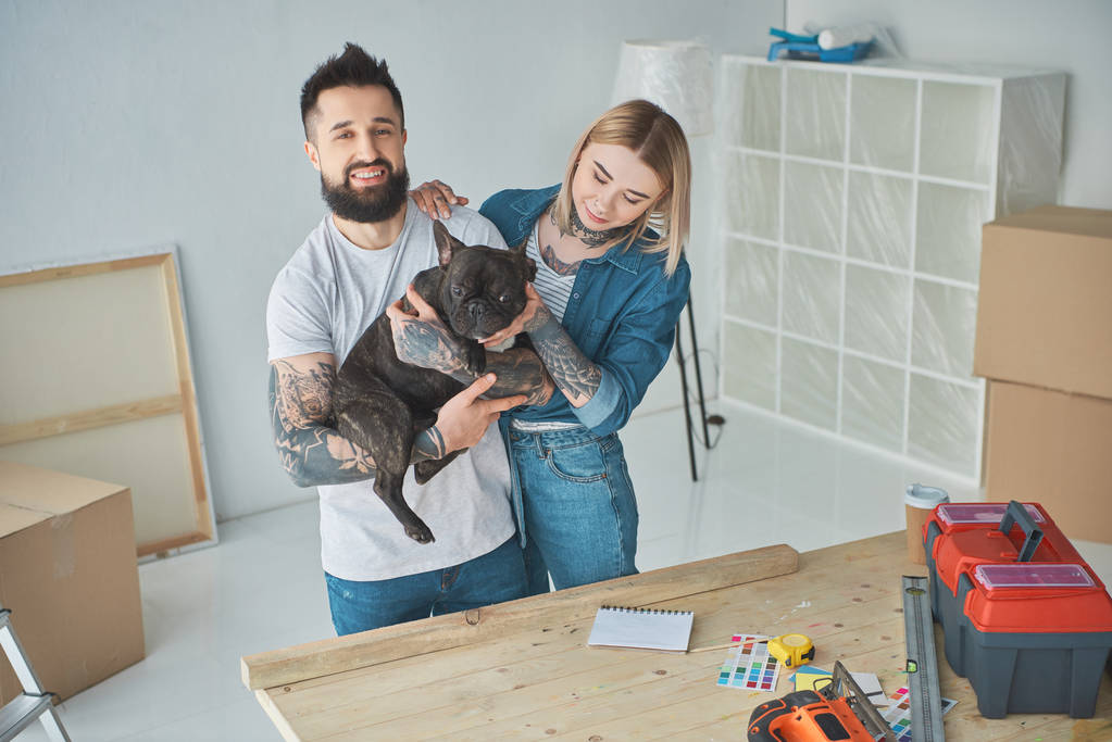 glückliches junges Paar spielt mit französischer Bulldogge beim Heimwerken - Foto, Bild