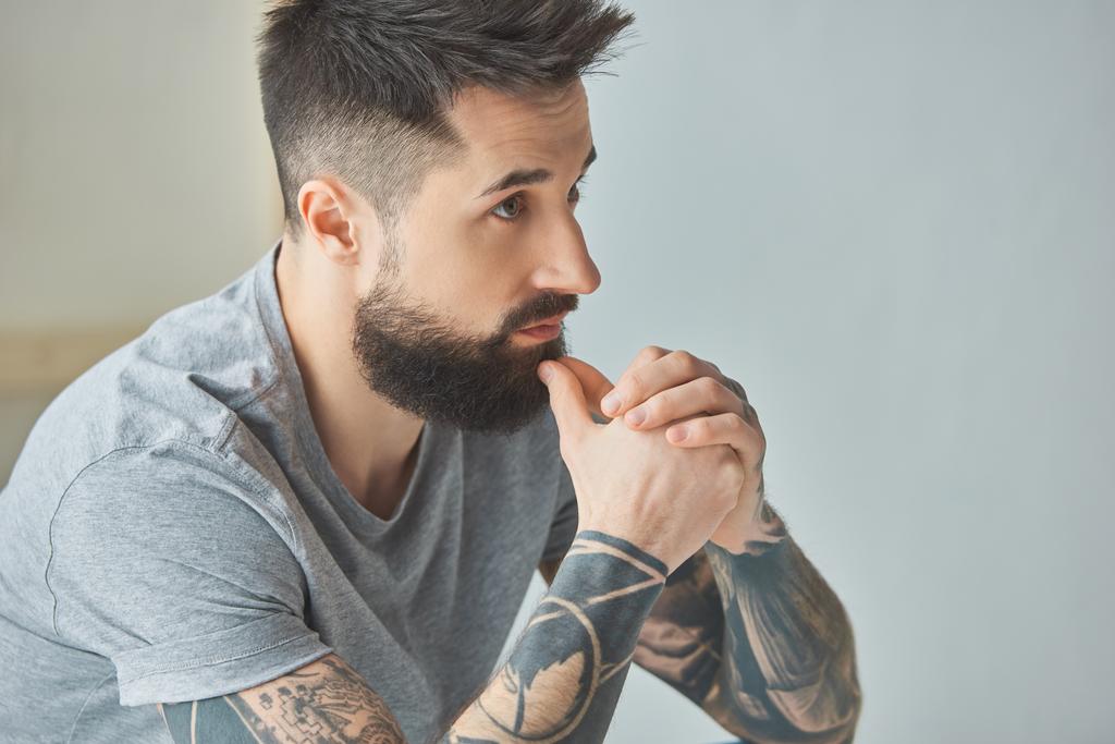 oldalnézetből a töprengő szakállas férfi keres el tetoválás - Fotó, kép