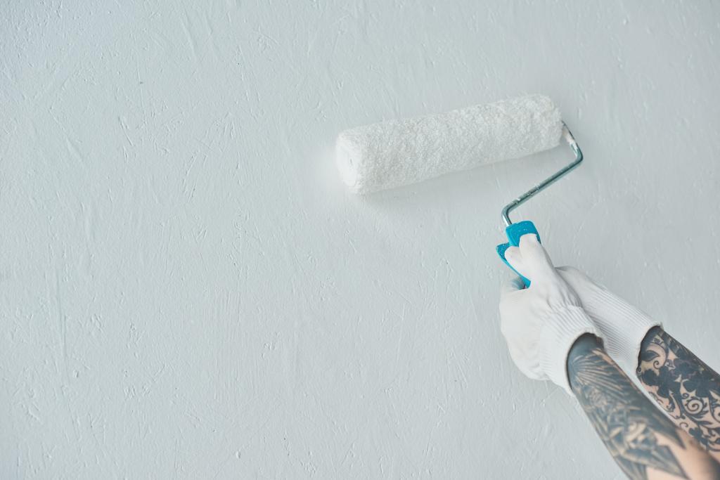 Kırpılan atış ile rulo boya fırça boyama duvar yeni evde dövmeli kadın - Fotoğraf, Görsel