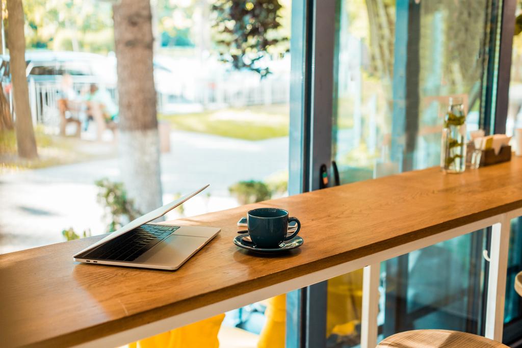 laptop and cup of coffee on wooden cafe counter - Photo, Image