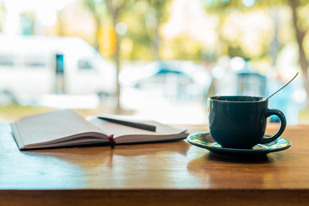 cup of coffee and open notebook with pen on wooden table in cafe - Photo, Image