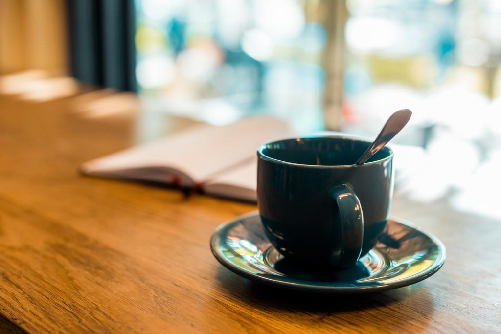 Tasse Kaffee mit Löffel auf Holztischplatte im Café - Foto, Bild