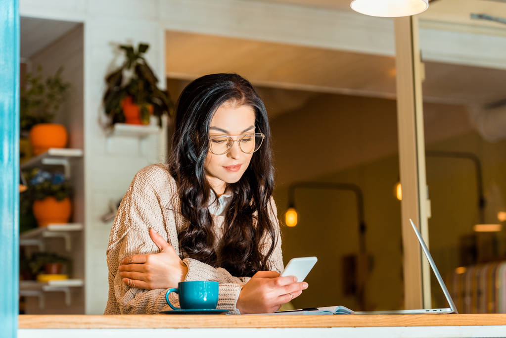 Piękna Brunetka kobieta za pomocą smartfona i laptop na przerwę na kawę w kawiarni - Zdjęcie, obraz