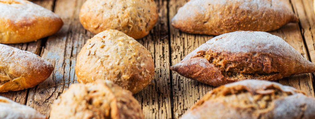 Diferentes tipos de pão fresco na mesa de madeira. Sortimento isolado de pão sobre fundo marrom
. - Foto, Imagem