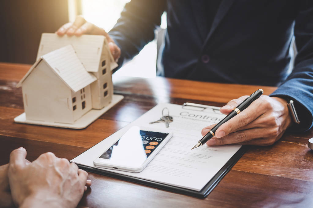 Immobilienmakler, der den Kunden zur Entscheidungsfindung präsentiert und berät, unterzeichnen Versicherungsformularvertrag, Hausmodell, betreffend Hypothekendarlehensangebot für und Hausversicherung. - Foto, Bild