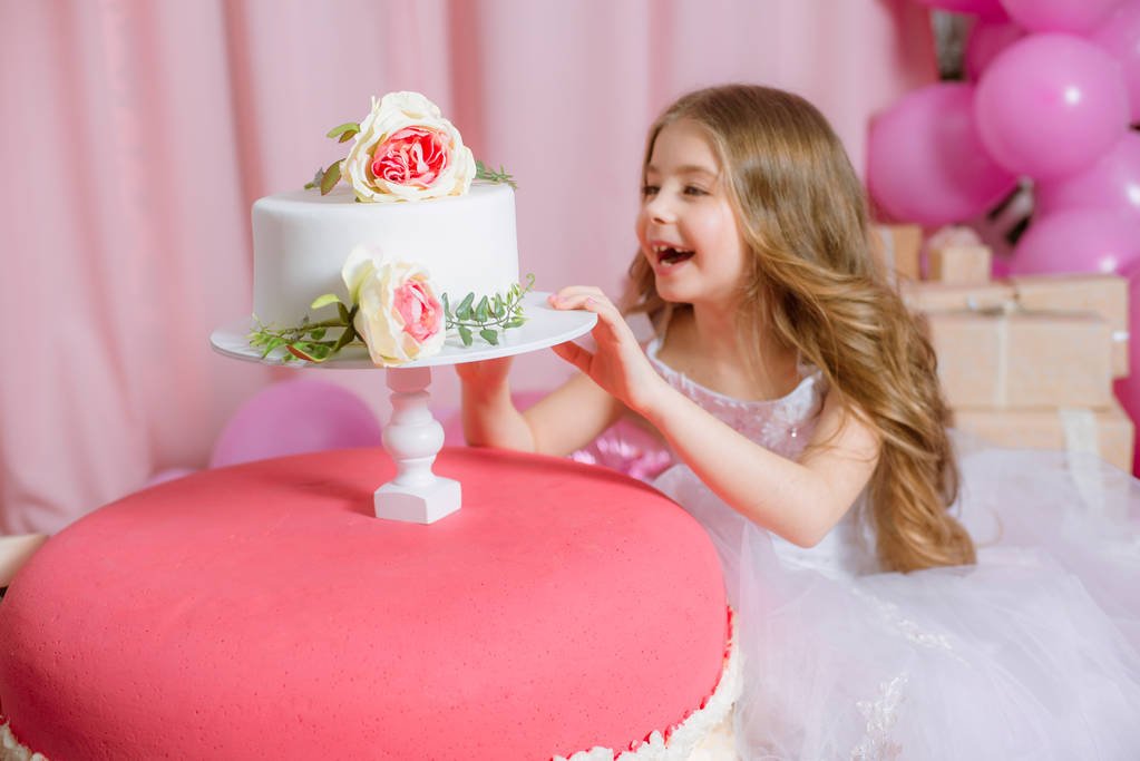 Meisje met blonde lange haren vieren Happy Birthday Party met rose decor, ballonnen en taart - Foto, afbeelding