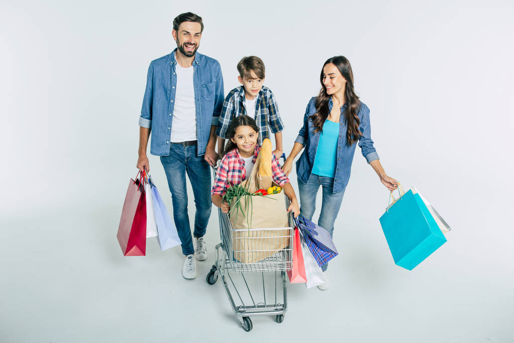 junge kaukasische Familie mit Einkaufstaschen auf weißem Hintergrund, Einkaufskonzept  - Foto, Bild