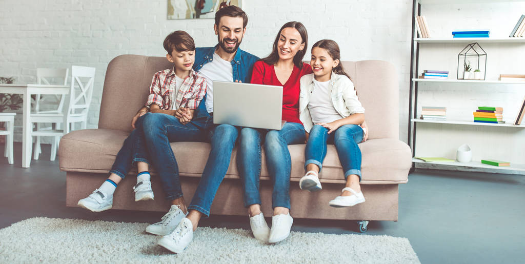 Jong gezin met behulp van laptop en thuis tijd doorbrengen - Foto, afbeelding