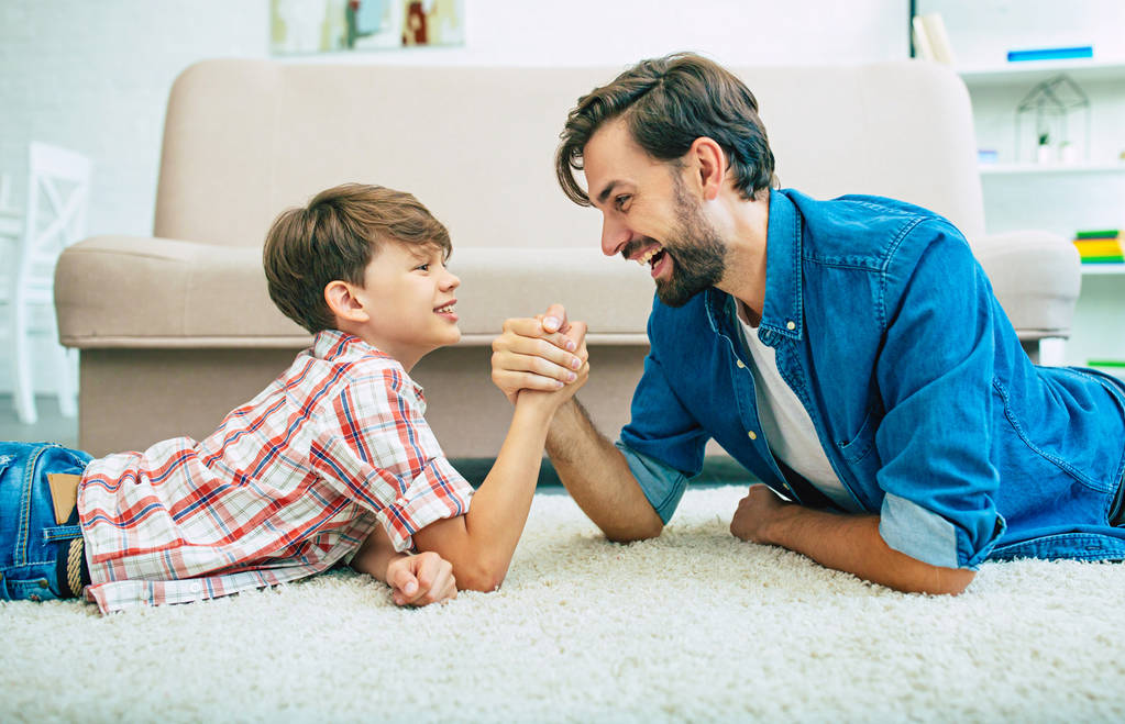 Νέος, χαμογελαστός ο πατέρας παίζει με το γιο του στο σπίτι - Φωτογραφία, εικόνα