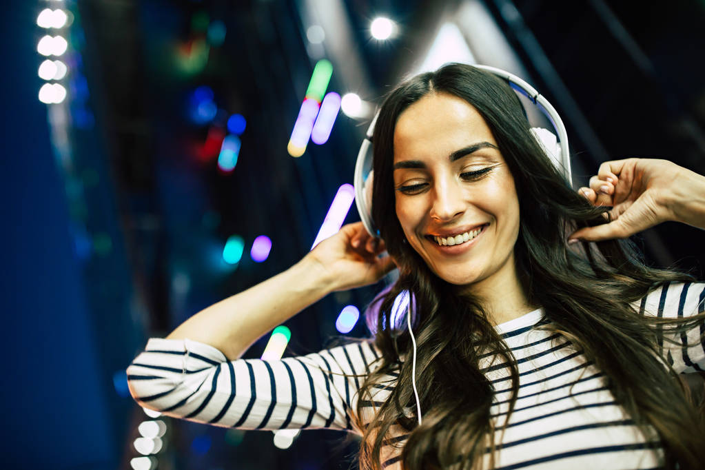 Fiatal, mosolygós nő zenehallgatás fejhallgató smartphone  - Fotó, kép