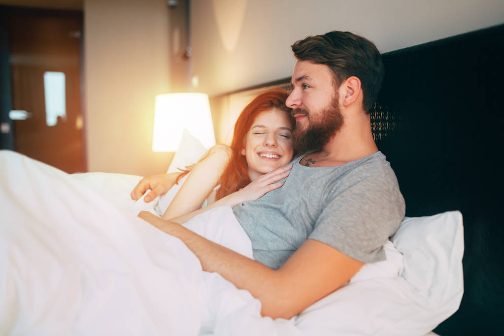 Αισθησιακό χαριτωμένο νεαρό ζευγάρι στο κρεβάτι αγκαλιά - Φωτογραφία, εικόνα