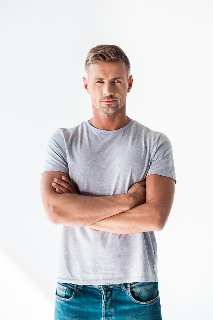 hombre adulto guapo en camiseta gris en blanco mirando a la cámara con los brazos cruzados aislados en blanco
 - Foto, Imagen