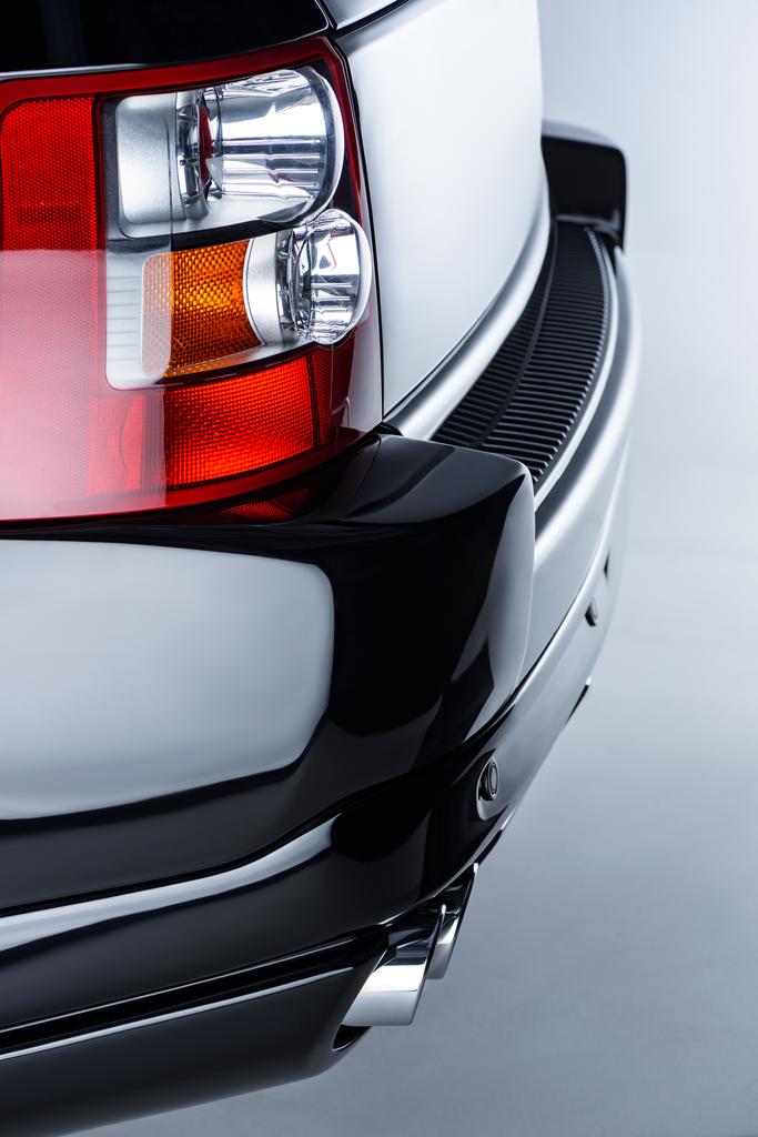 Close-up van achterste koplamp van zwarte luxeauto op grijze achtergrond - Foto, afbeelding