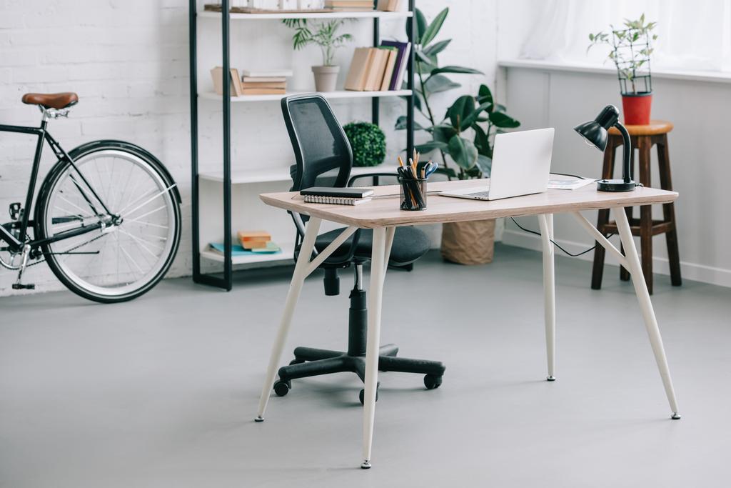 テーブル、ノート パソコンとバイクと近代的なビジネス オフィスのインテリア - 写真・画像
