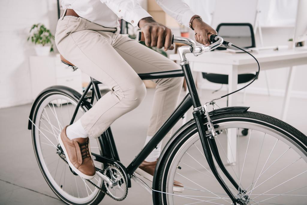 image recadrée de l'homme d'affaires afro-américain à vélo dans le bureau
 - Photo, image