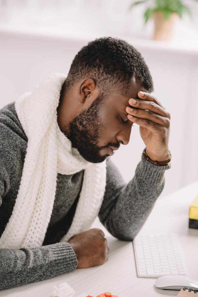 müde junge afrikanisch-amerikanische Mann mit Kopfschmerzen sitzt im Büro  - Foto, Bild