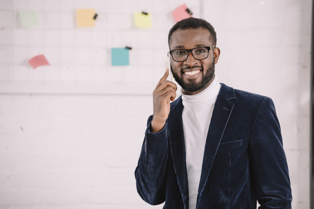 χαμογελώντας Αφρικανικός Αμερικανός επιχειρηματίας σε βελούδινο σακάκι, μιλάμε για το smartphone  - Φωτογραφία, εικόνα