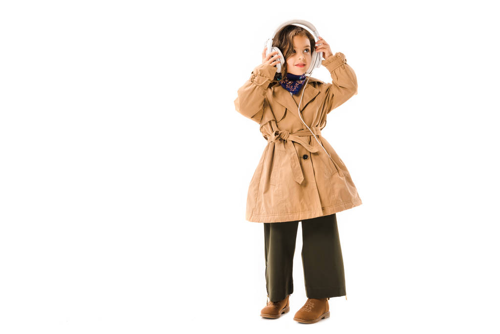 linda criança em casaco de trincheira com fones de ouvido isolados em branco
 - Foto, Imagem