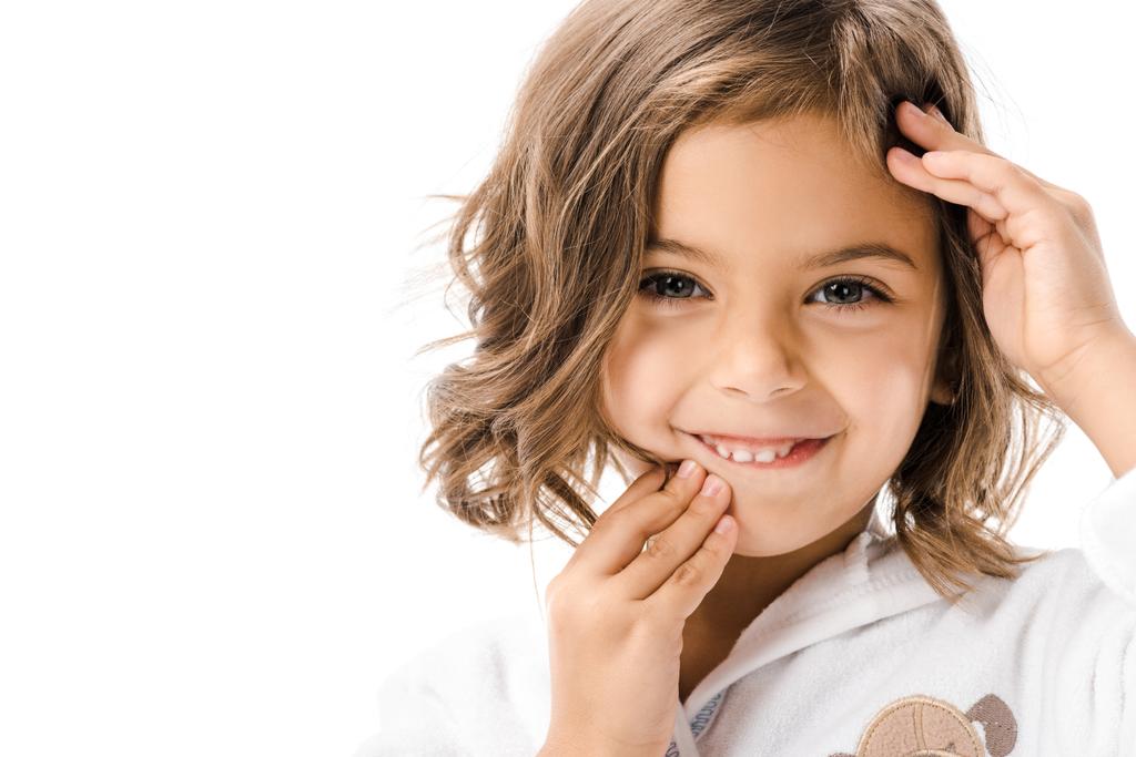 portrét usměvavého dítěte dotýkat tváře a při pohledu na fotoaparát izolované na bílém - Fotografie, Obrázek