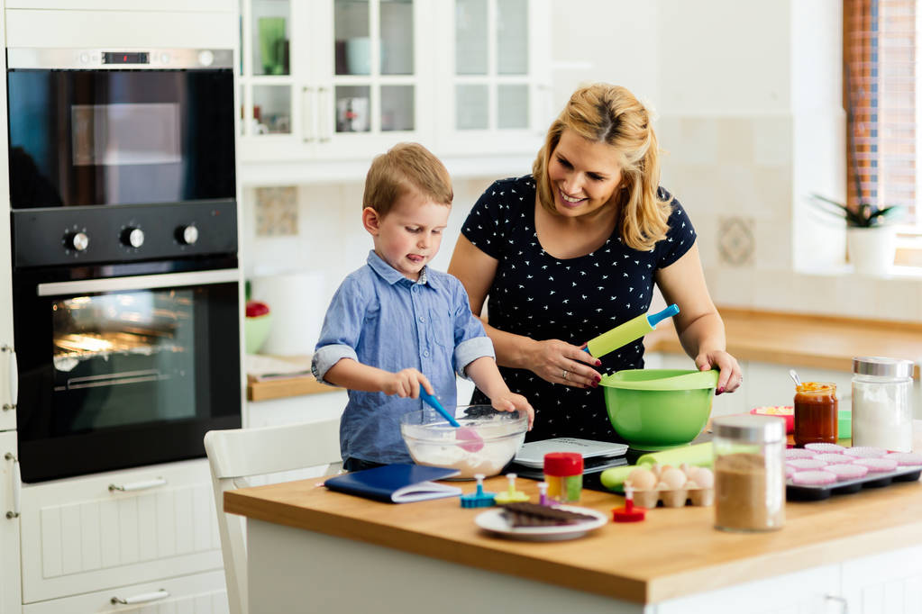 Enfant aidant mère à faire des biscuits dans la cuisine moderne
 - Photo, image