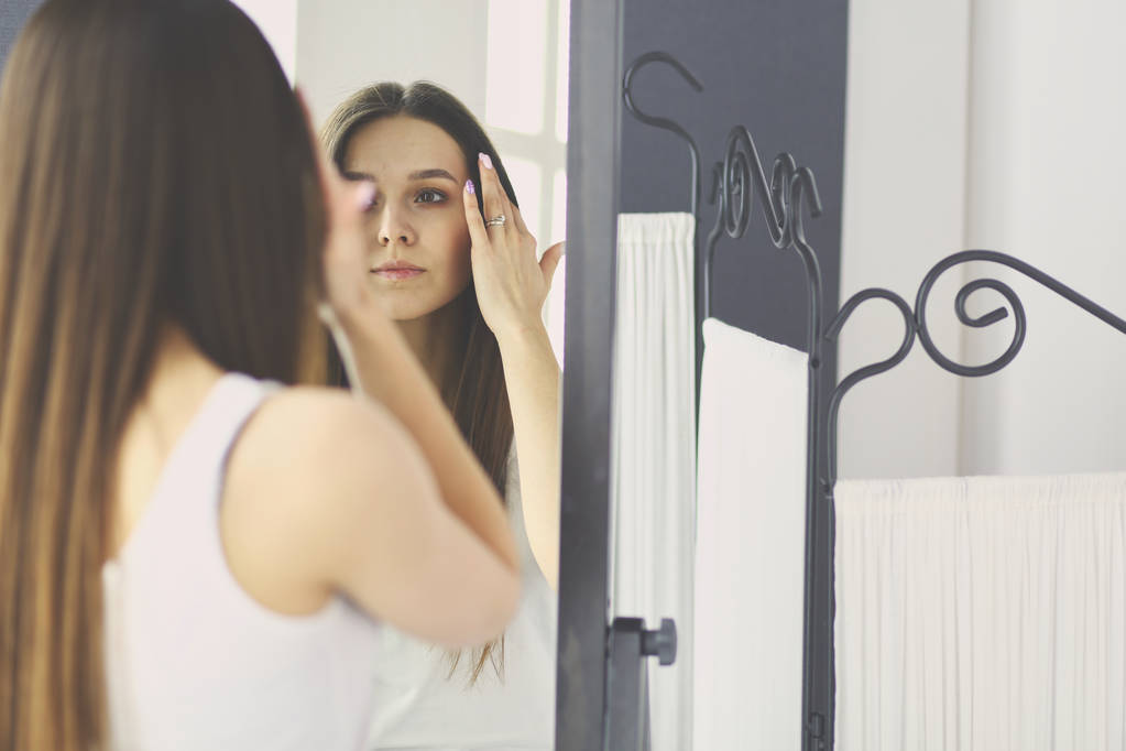 Mujer joven mirándose a sí misma reflejo en el espejo en casa
. - Foto, Imagen
