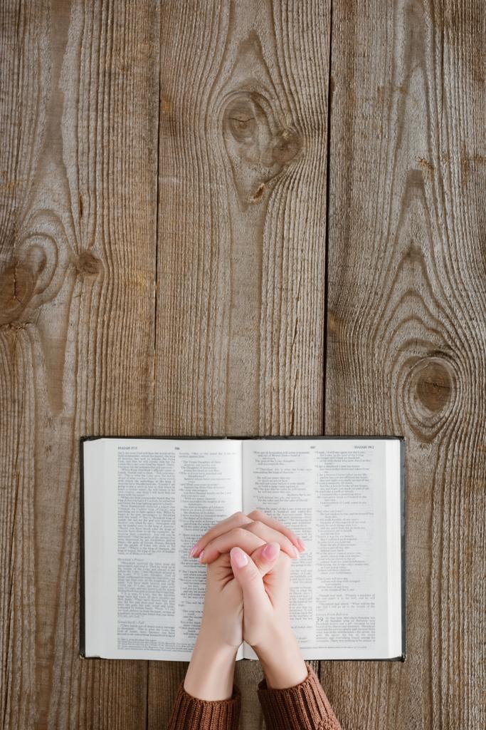 bijgesneden schot van vrouw bidden met de Bijbel op houten tafel - Foto, afbeelding