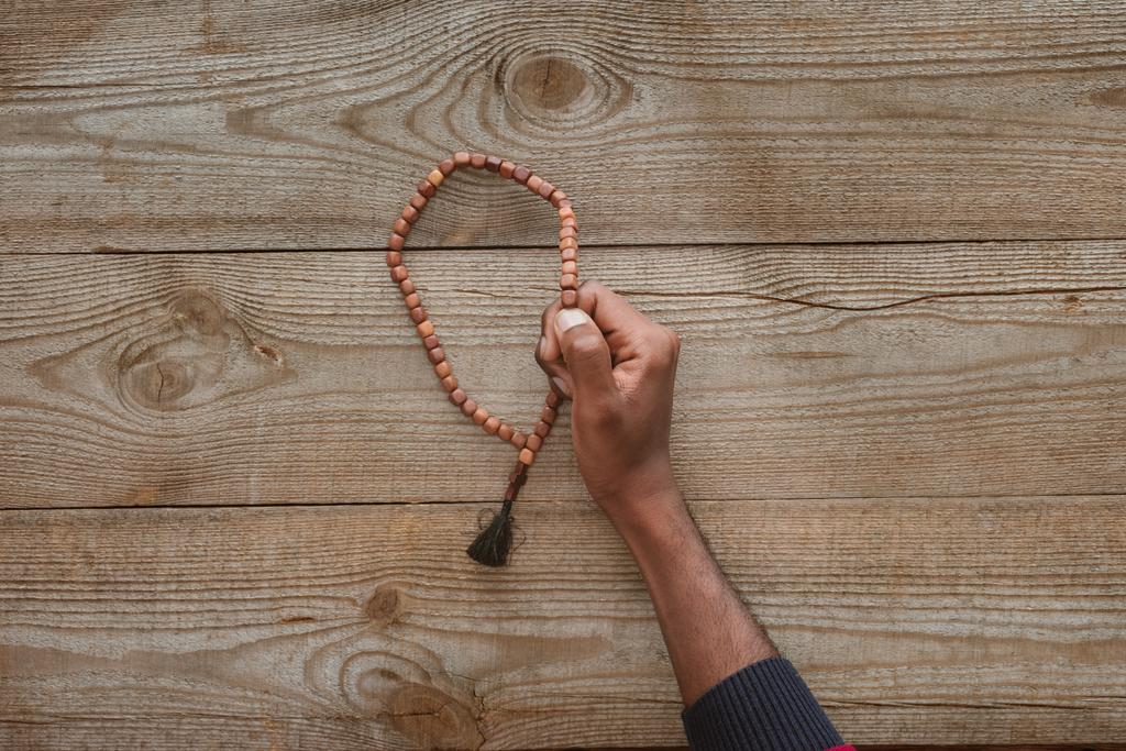 Schnappschuss eines Afroamerikaners mit Perlen auf Holztisch - Foto, Bild