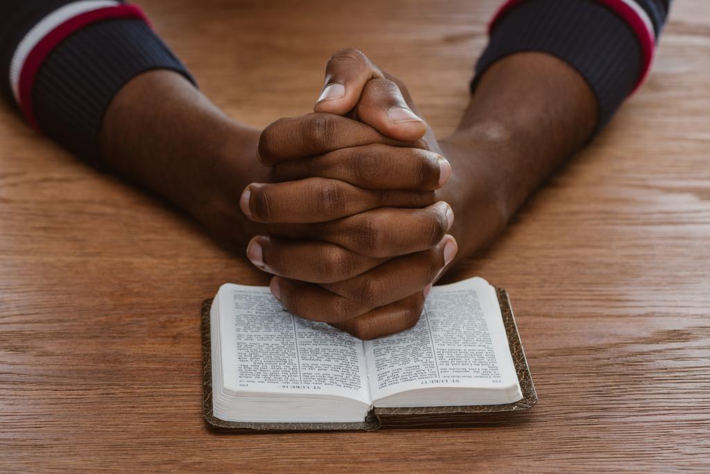 przycięty Zrzut z african american człowiek modli się z Pisma Świętego - Zdjęcie, obraz