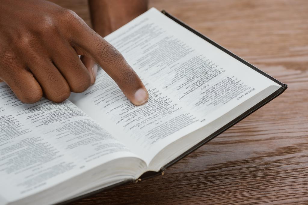 przycięty Zrzut z african american man, czytanie Pisma Świętego i wskazując na psalm - Zdjęcie, obraz