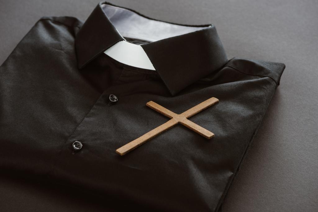 primer plano de camisa clerical con cruz sobre superficie gris
 - Foto, Imagen