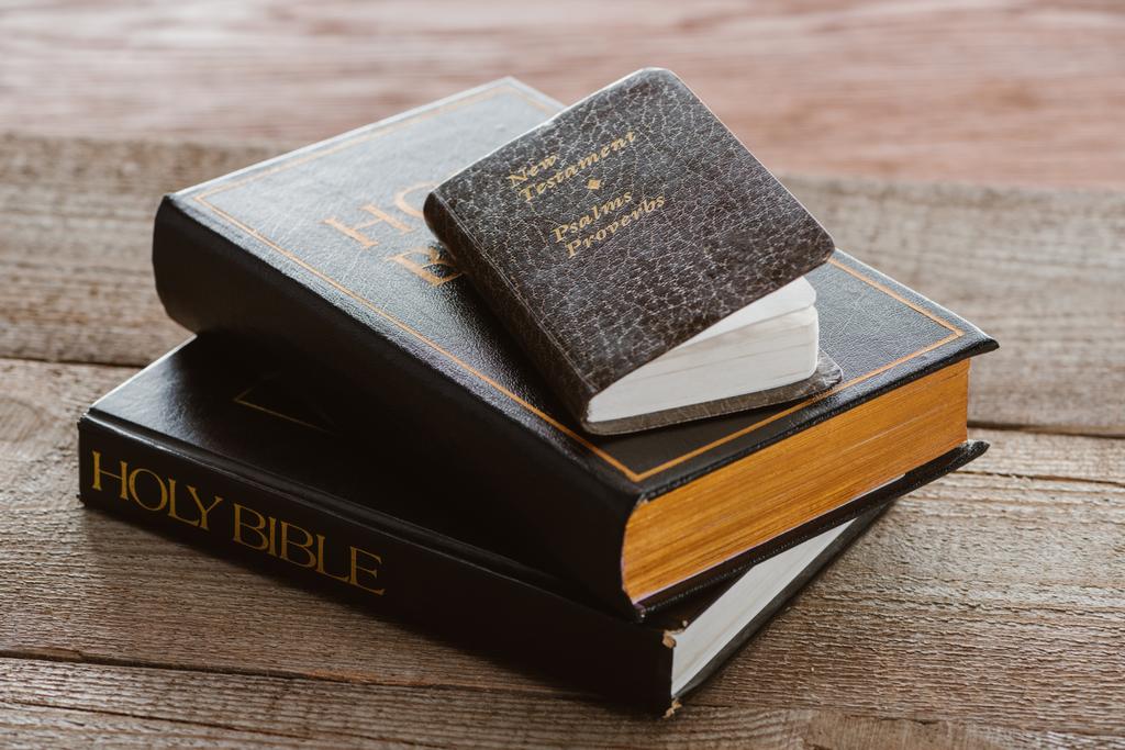close-up shot of stacked holy bibles with new testament book on wooden surface - Photo, Image