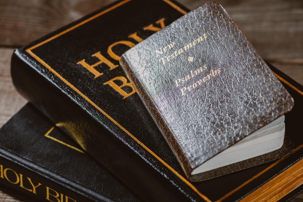 közeli lövés halmozott Szent Bibliát újszövetségi könyv a fából készült asztallap - Fotó, kép