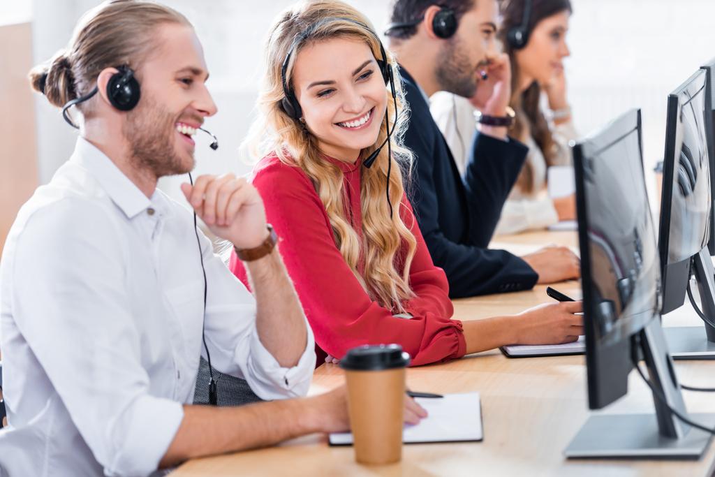 foco seletivo de operadores de call center sorridentes trabalhando no local de trabalho com café para ir no escritório
 - Foto, Imagem